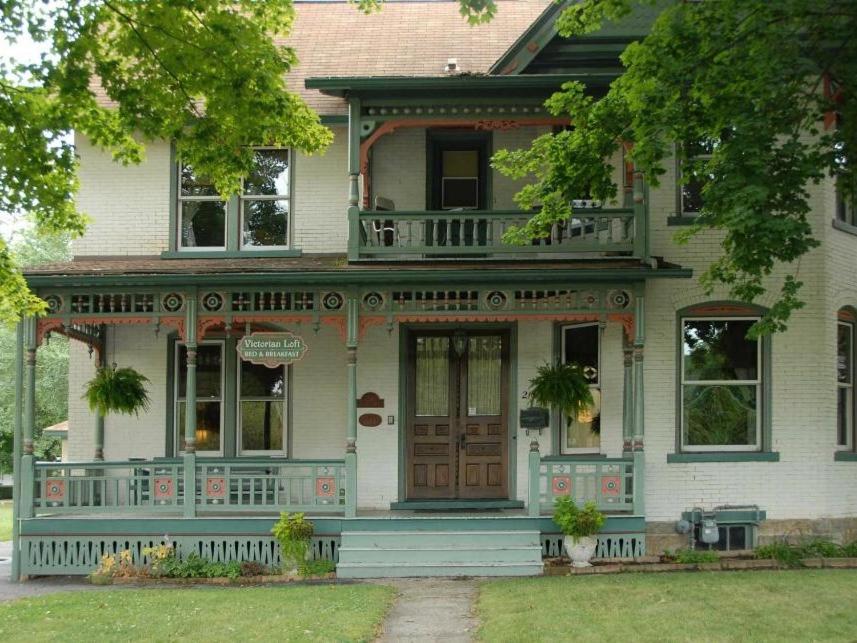 a white house with a porch and a wooden door at Victorian Loft Bed and Breakfast in Clearfield