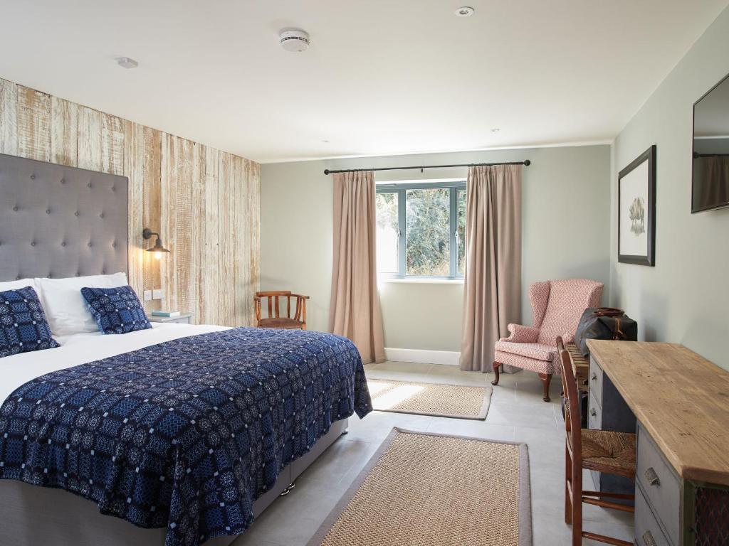 um quarto com uma cama, uma cadeira e uma janela em The Pig Shed Motel em Castle Acre
