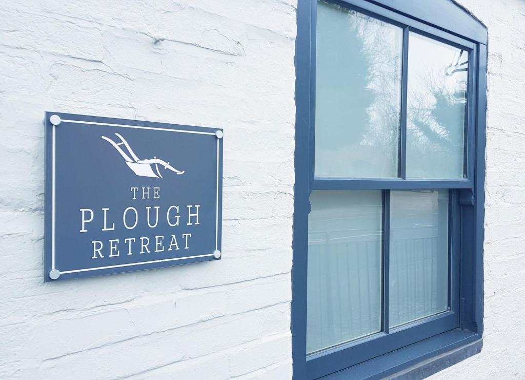 a sign on the side of a building with a window at The Plough Retreat in Coddington