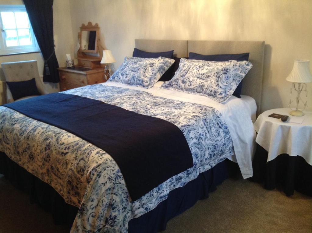 una camera da letto con un grande letto con lenzuola blu e bianche di Primrose Cottage a Norwich