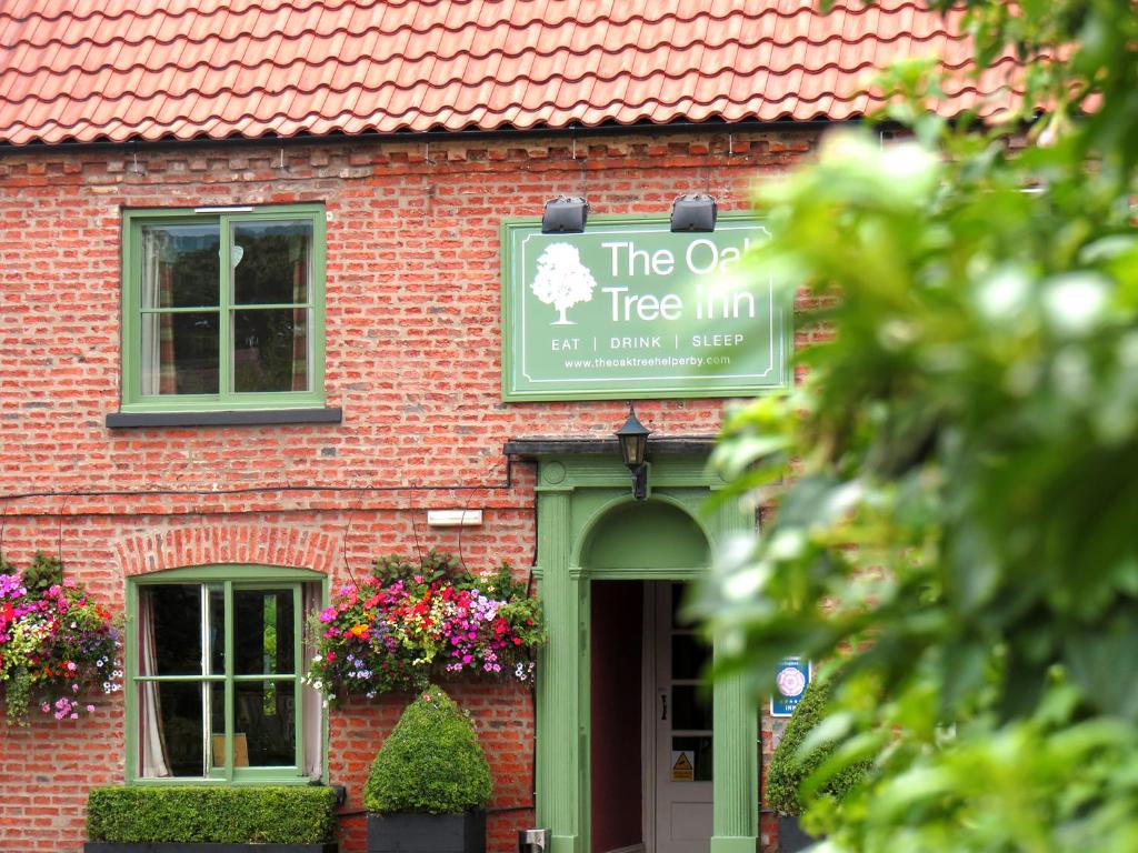 a tree inn sign on the side of a brick building at Oak Tree Inn in Brafferton