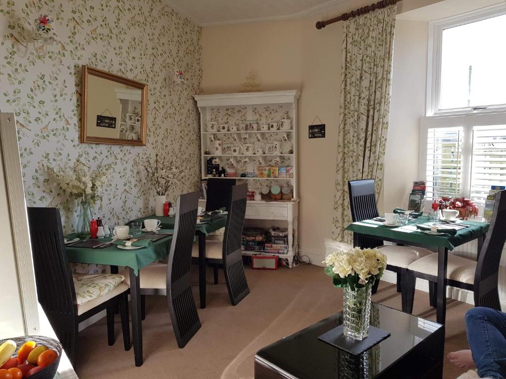 a dining room with green tables and chairs at The Pavilion Guest House in Millom