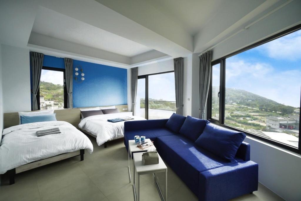 a hotel room with a blue couch and a bed at 東莒 找茶複合式民宿-連江縣民宿199號 in Juguang