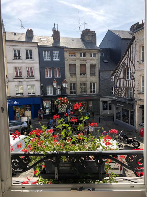 a view of a city from a window with flowers at L'Appartement R Postel (4/6 Pers) in Honfleur