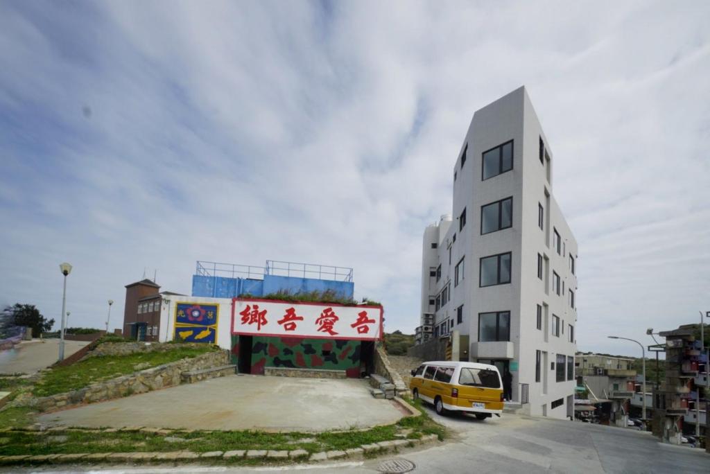 a yellow van parked next to a white building at 東莒 找茶複合式民宿-連江縣民宿199號 in Juguang