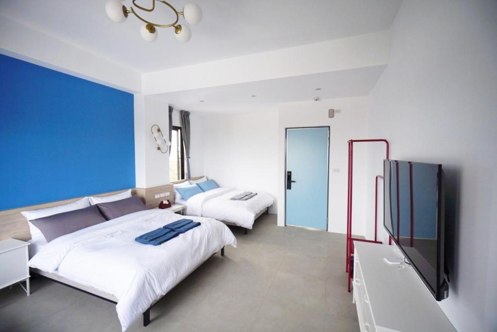 a bedroom with two beds and a flat screen tv at 東莒 找茶複合式民宿-連江縣民宿199號 in Juguang