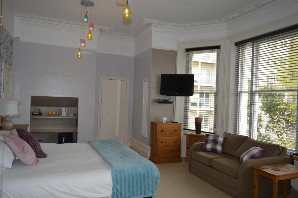 a bedroom with a bed and a couch and a tv at The Sheldon B&B - FREE private parking in Eastbourne