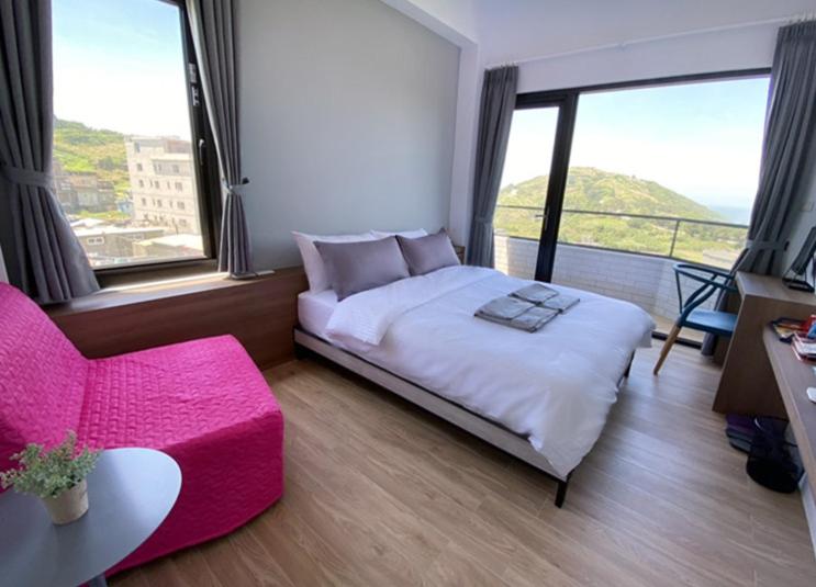 a bedroom with a large bed and a pink chair at 東莒 找茶複合式民宿-連江縣民宿199號 in Juguang