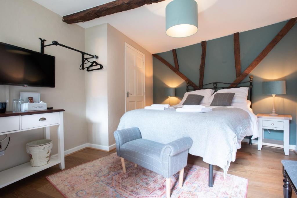 Un dormitorio con una cama, un televisor y una silla. en The Talkhouse, en Stanton Saint John