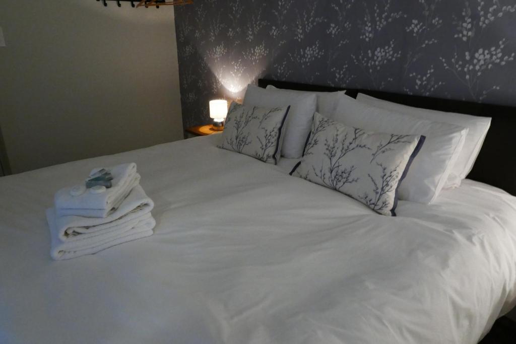 uma cama com lençóis brancos e almofadas com toalhas em The Victoria em Malham