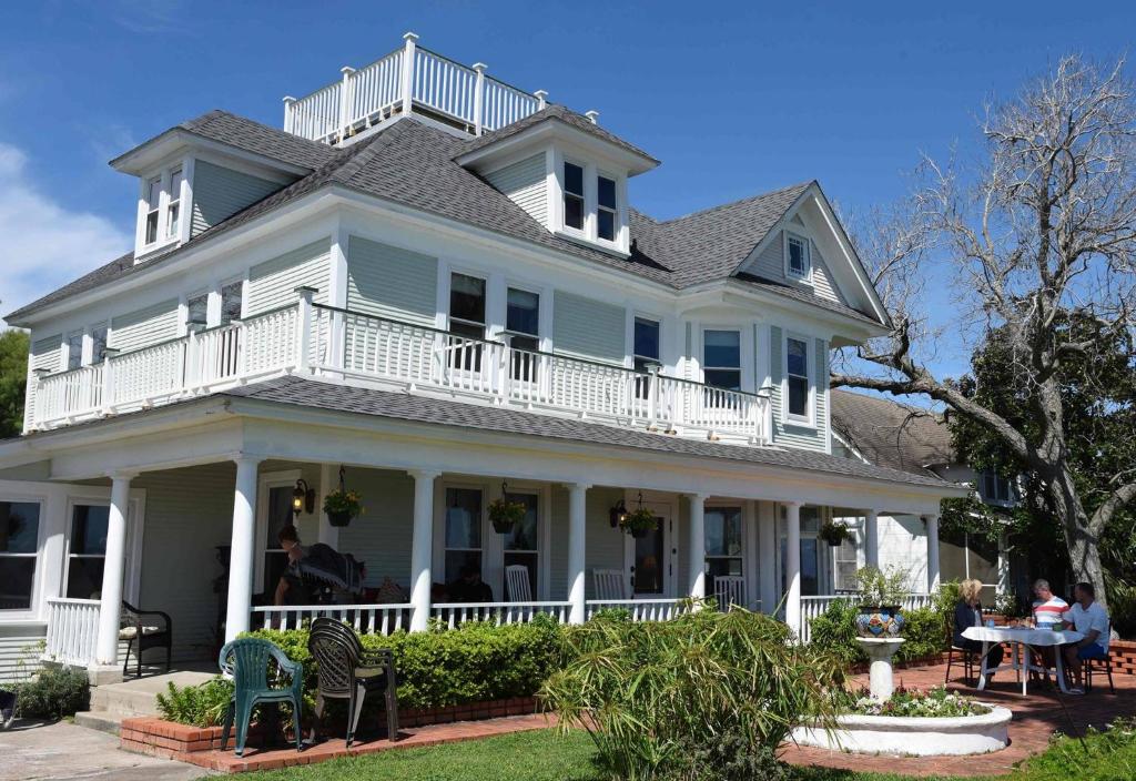 a large white house with people sitting at a table at The Peaceful Pelican LLC in Palacios