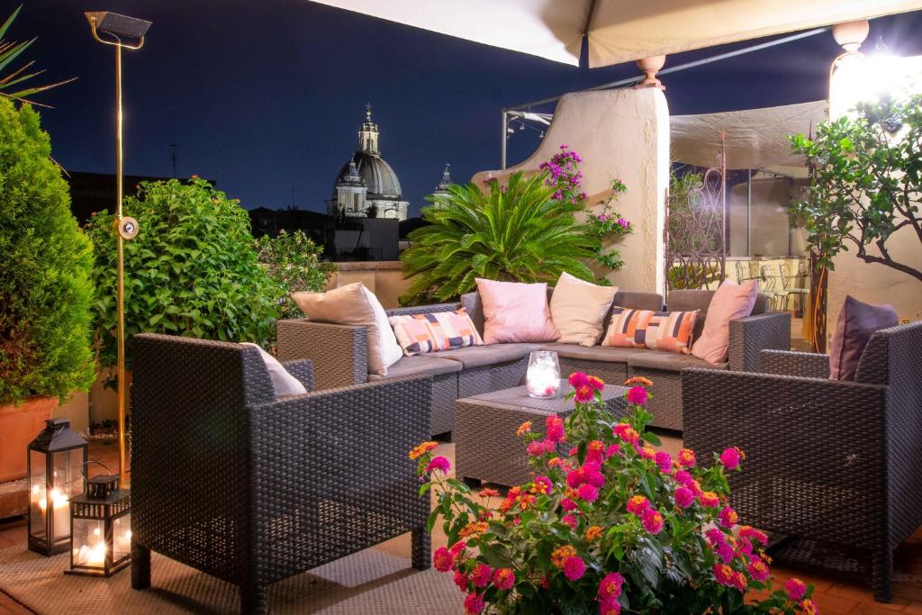 eine Terrasse mit einem Sofa, Stühlen und Blumen in der Unterkunft Sant'Ivo Apartments in Rom