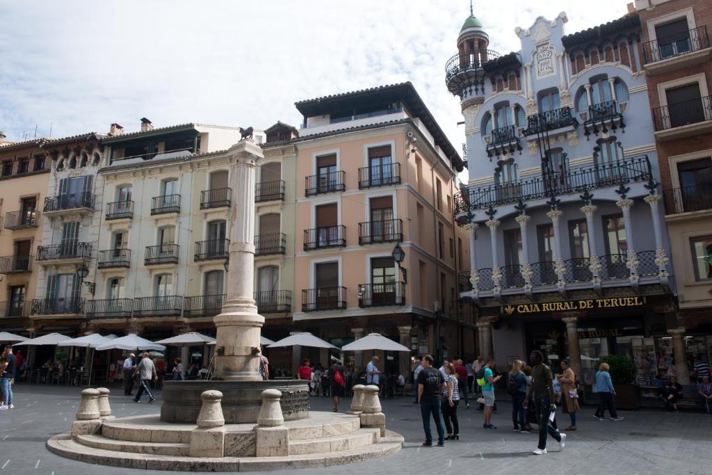 a group of people standing around a fountain in a street at Apartamentos Plaza del Torico Teruel in Teruel