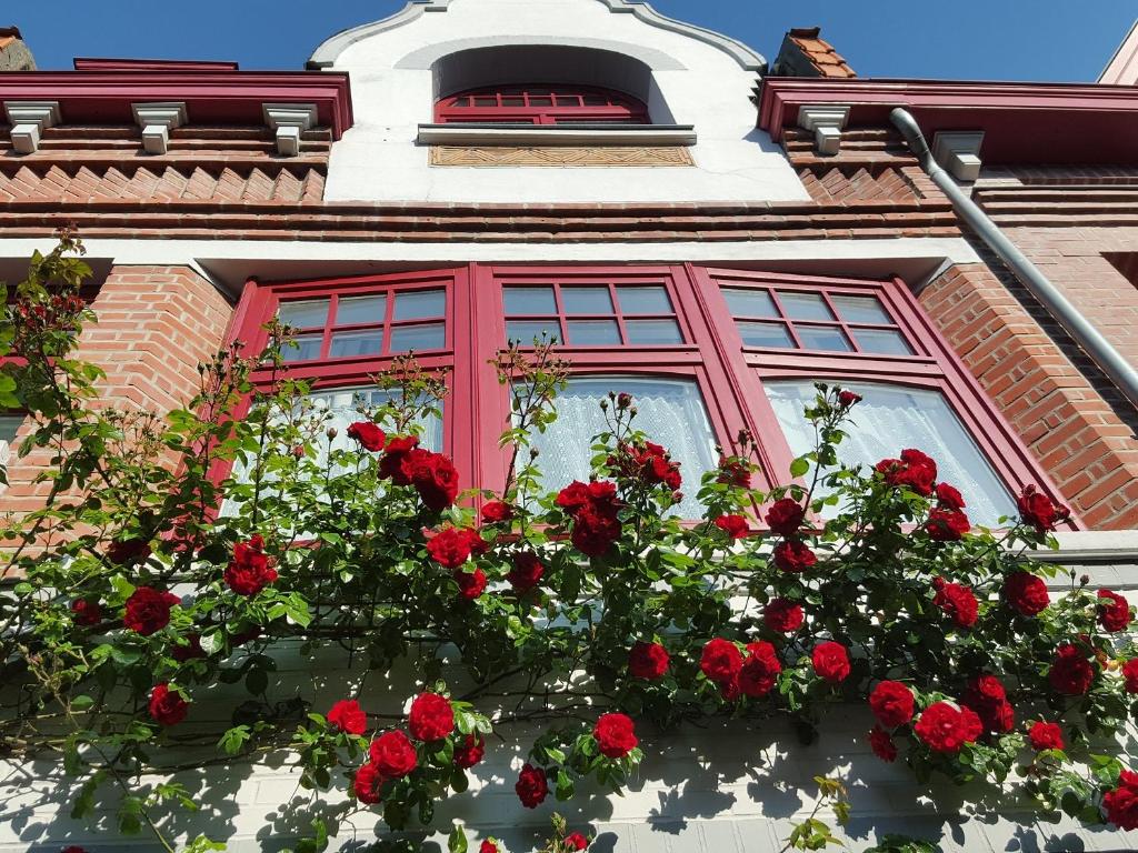 a window with red roses in front of a building at Au Troubadour in Hellemmes-Lille