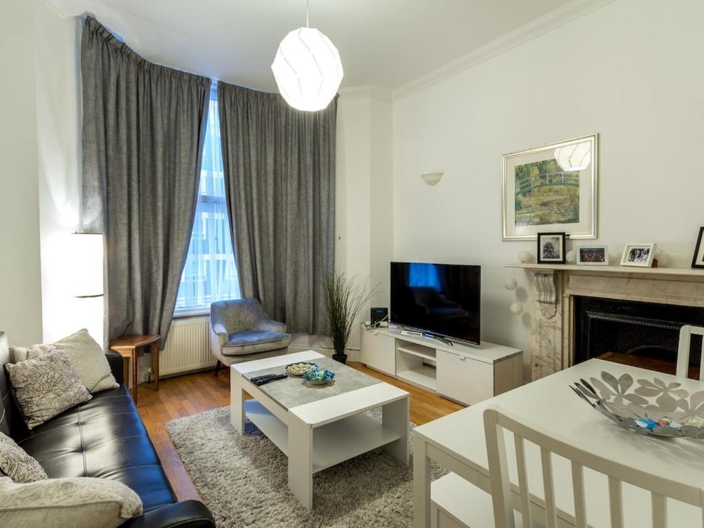uma sala de estar com um sofá e uma mesa em Spacious 1 Bed in West Kensington or Hammersmith em Londres