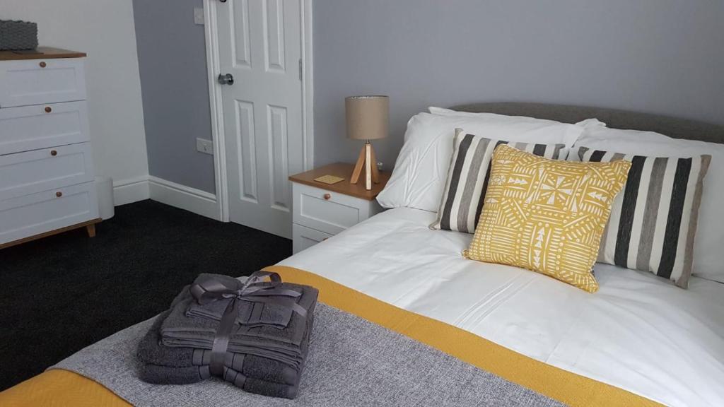 Townhouse @ Birches Head Road Stoke في ستوك أون ترينت: غرفة نوم مع سرير مع حقيبة ظهر عليه
