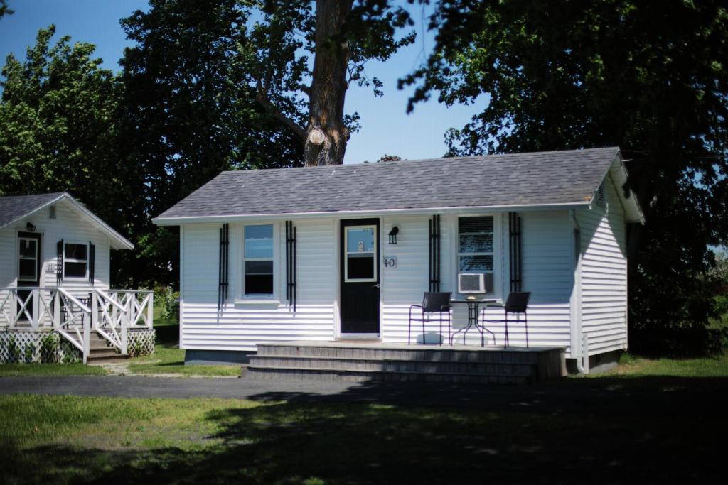 a white house with a porch with two chairs at CARLETON INN & COTTAGES in Bridgetown