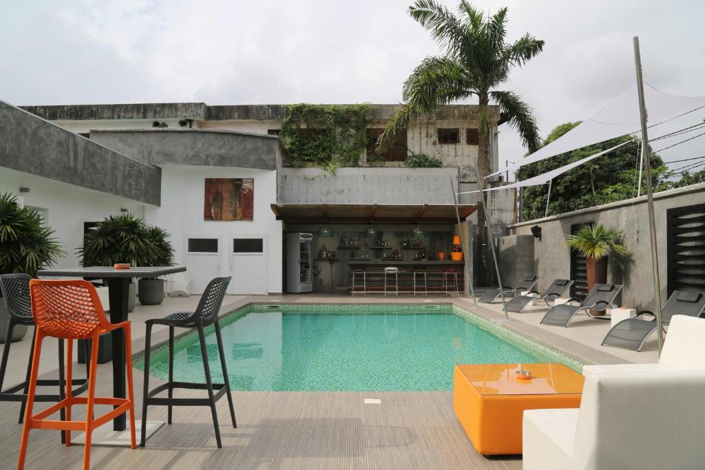a pool with chairs and a table next to a building at Stanislas Maison d'hotes in Abidjan