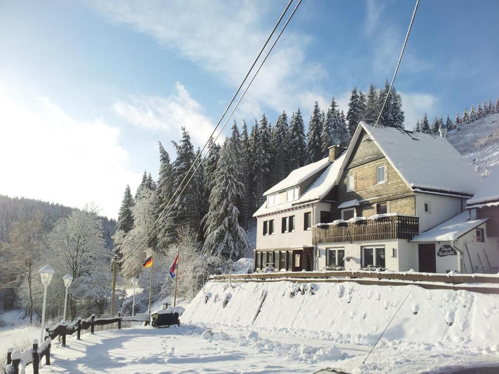 una casa al lado de una carretera cubierta de nieve en Landgasthof Nesselbach, en Schmallenberg
