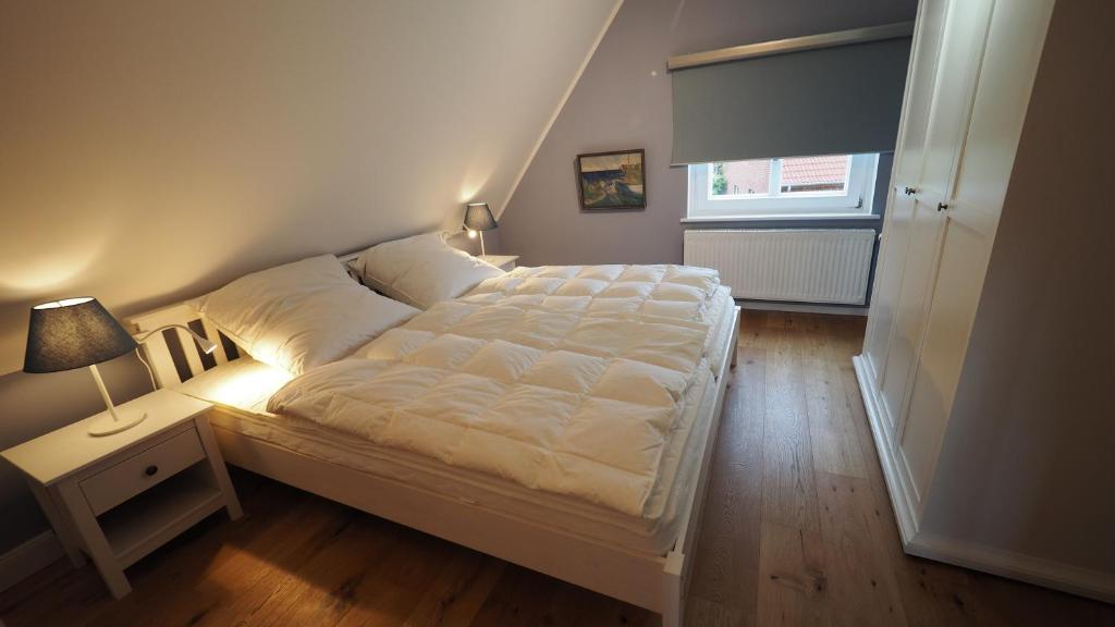 ein Schlafzimmer mit einem Bett und einem Tisch mit einer Lampe in der Unterkunft Ostseehaus Heisterbusch in Kellenhusen