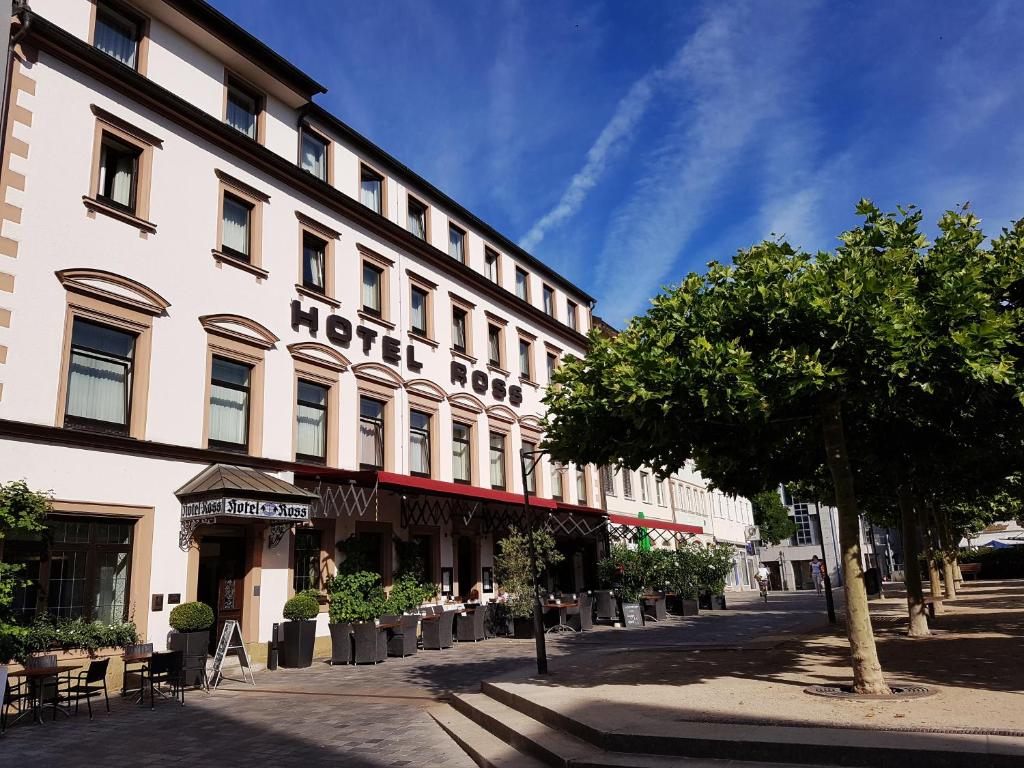 un edificio de hotel en una calle de la ciudad con un árbol en Hotel Ross en Schweinfurt