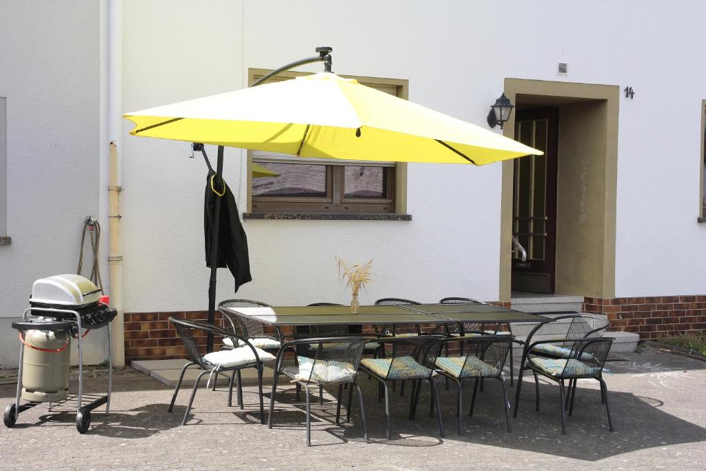 a table with a yellow umbrella and chairs at Bike and Hike Ferienhaus Kolverath in Kolverath