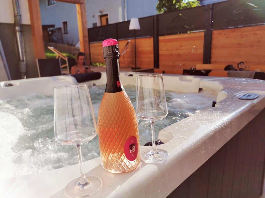 una bottiglia di champagne e 2 bicchieri di vino in una vasca idromassaggio di Grand Chalet Hochfilzen a Hochfilzen