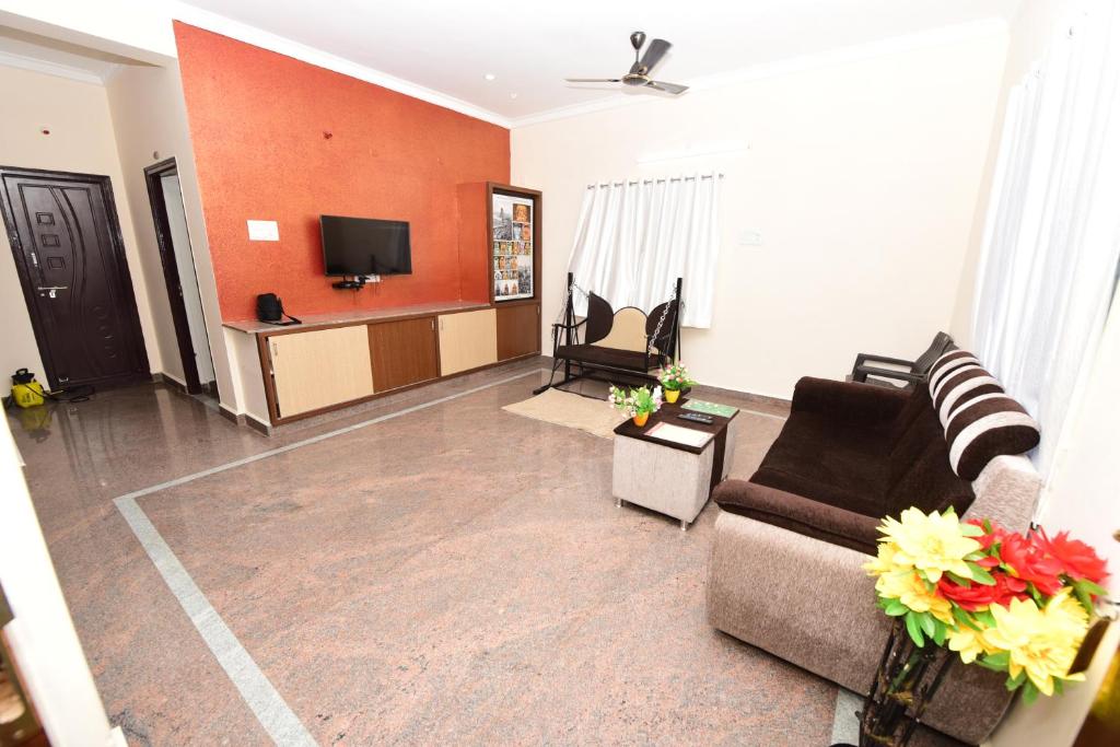 Il comprend un salon avec des canapés et une télévision à écran plat. dans l'établissement Sree Service apartments, à Tirupati