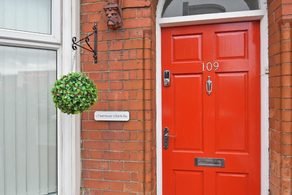 a red door on a brick building with a plant at Townhouse @ Earle Street Crewe in Crewe