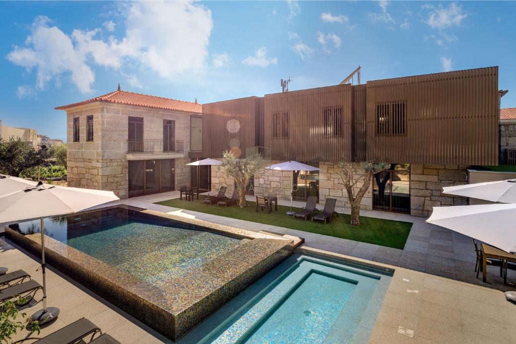 a swimming pool with umbrellas and a building at Quinta do Aido - WineTourism in Cinfães