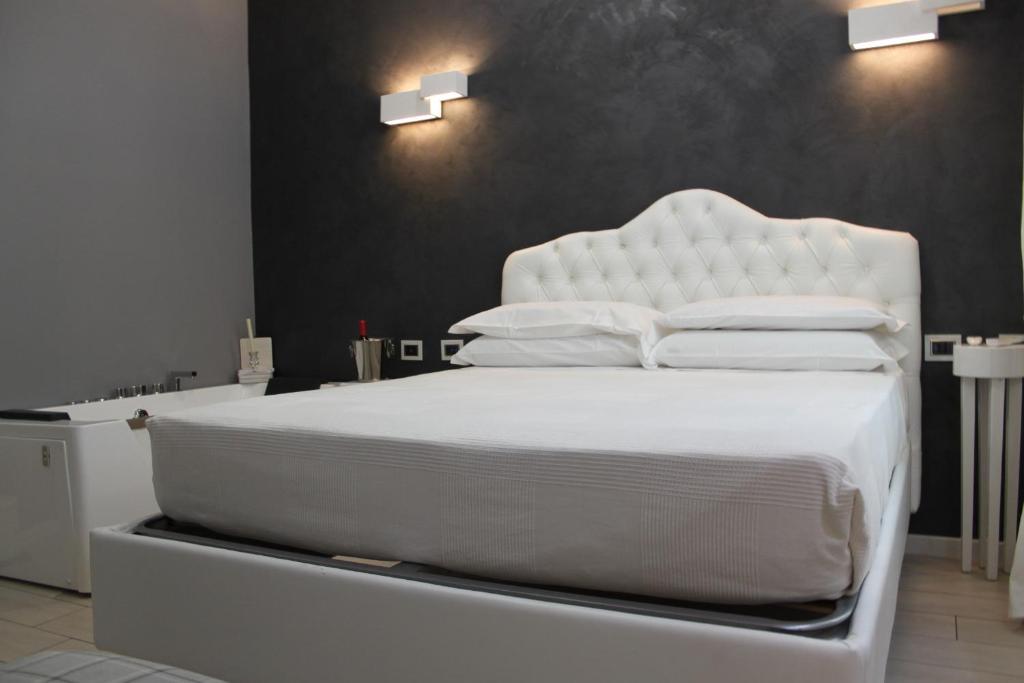- un lit blanc avec des draps et des oreillers blancs dans l'établissement Jacuzzi apartament by parmacentro b&b, à Parme