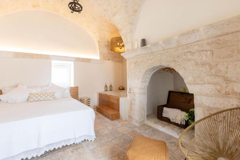 a bedroom with a white bed and a fireplace at Caterina's Suites & Apartament in Ostuni