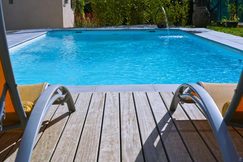 a swimming pool with a wooden deck and a swimming pool at La Maison Des Artistes in Tourrette-Levens