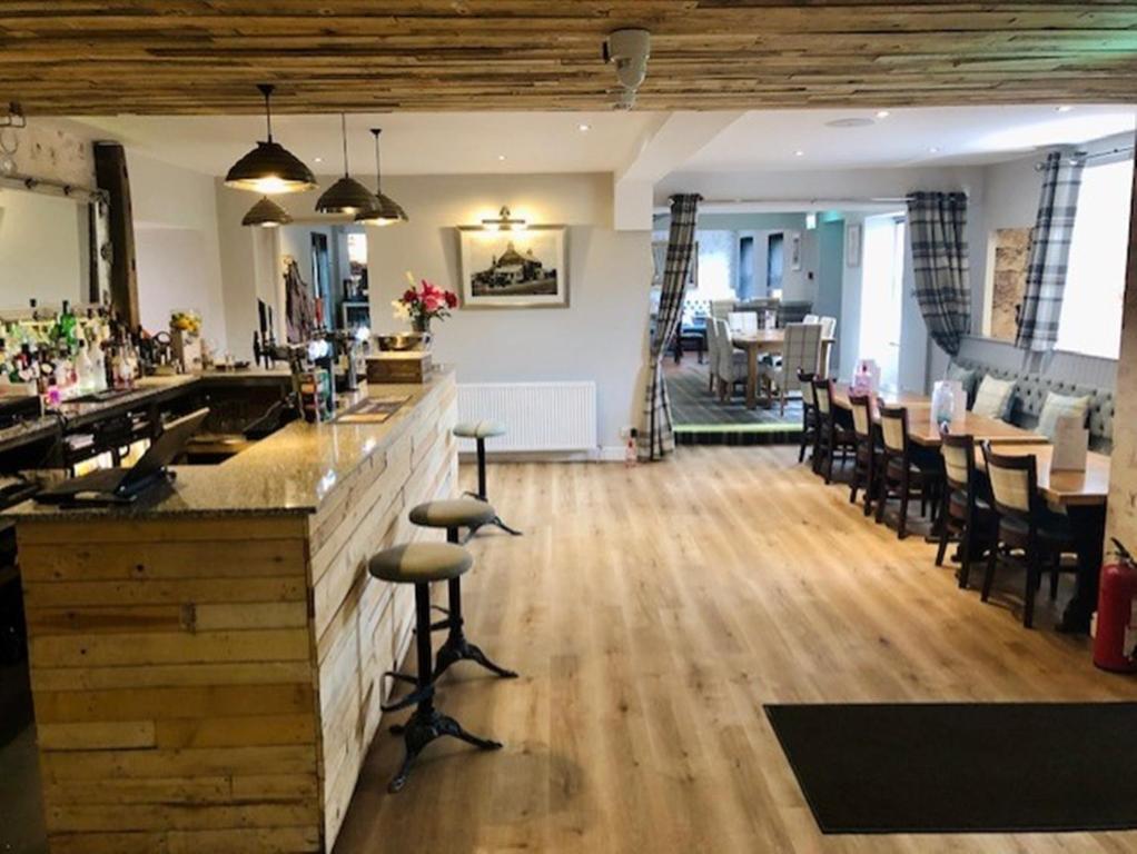 a bar in a restaurant with wooden floors and chairs at The Juniperlea Inn in Pathhead