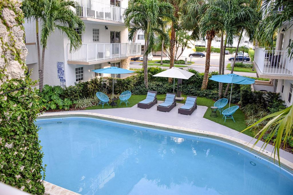 a swimming pool with chairs and umbrellas in front of a building at Coral Reef at Key Biscayne in Miami