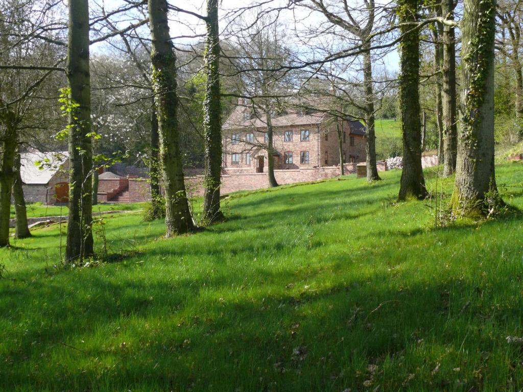 un campo con árboles y una casa al fondo en The Larches Ledbury en Ledbury