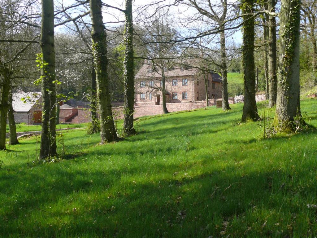 a field with trees and a house in the background at The Larches Ledbury in Ledbury