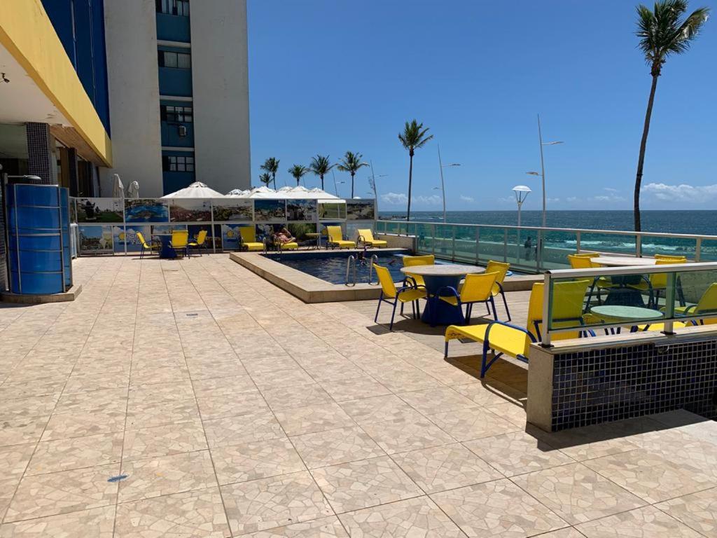 un patio con mesas y sillas amarillas y el océano en Bahia Flat - Barra, en Salvador