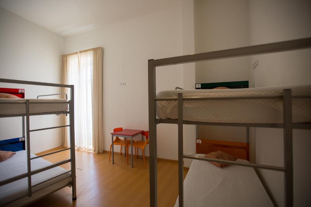 a room with three bunk beds and a table at HI Tavira – Pousada de Juventude in Tavira