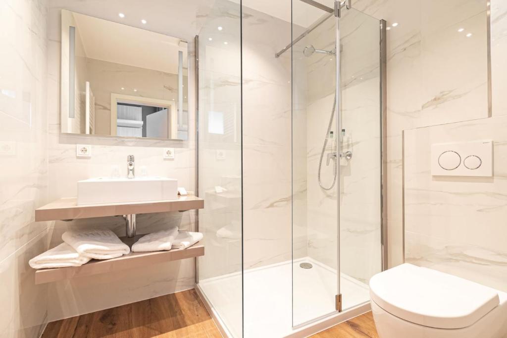 a bathroom with a shower and a sink and a toilet at Hotel Re'ser Stuff in Roeser