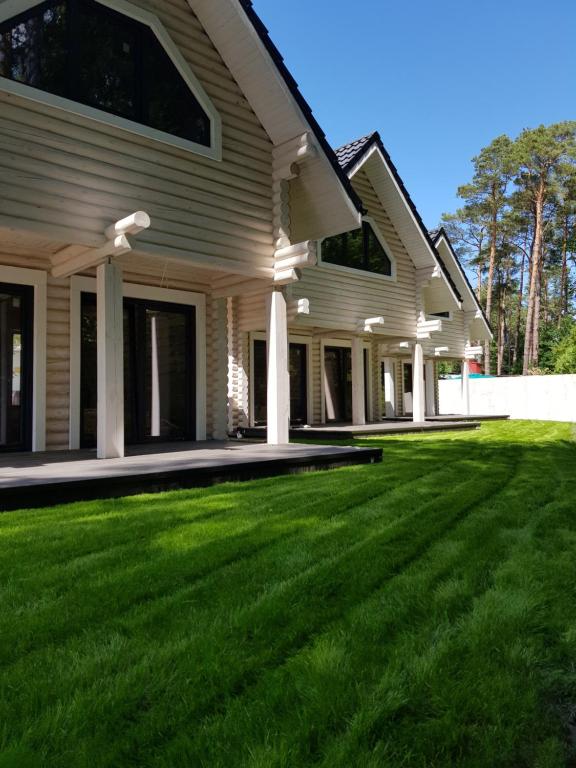 a house with a green lawn in front of it at Vega Apartamenty in Pobierowo