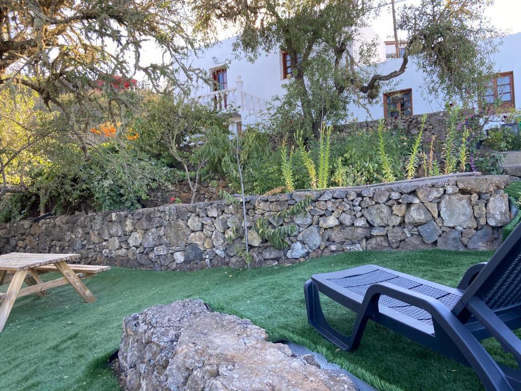 un patio con un banco y una pared de piedra en CASAS RURALES TIO ANTONIO, en Las Rosas