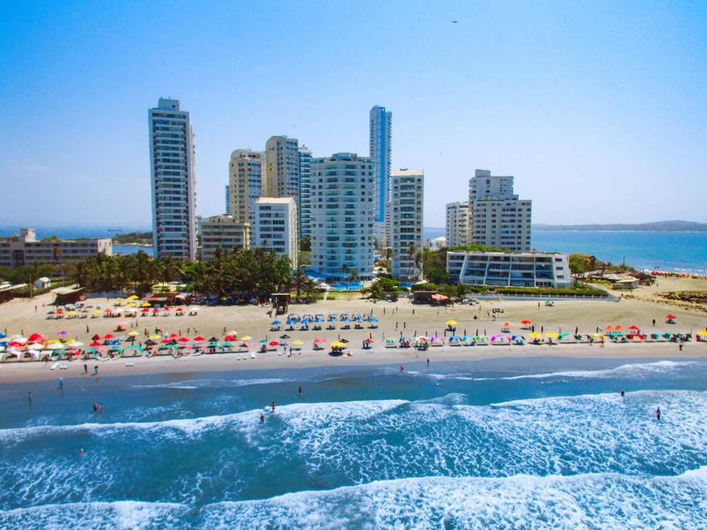 ein Strand mit Menschen und Sonnenschirmen und eine Stadt in der Unterkunft Hotel Dann Cartagena in Cartagena de Indias
