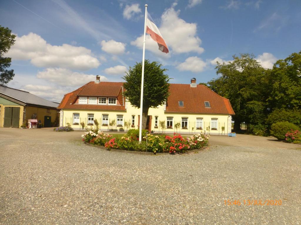 a flag pole in front of a white building at Ferienhof Lorenzen in Dörphof
