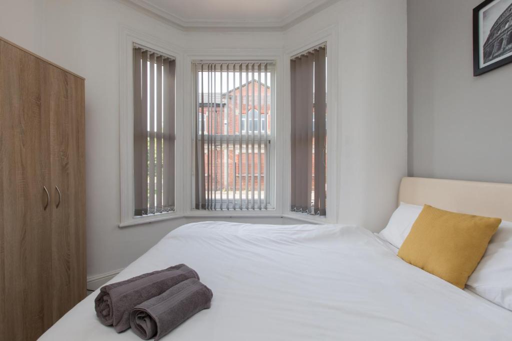 a bedroom with a white bed with two towels on it at Townhouse @ Electricity Street Crewe in Crewe