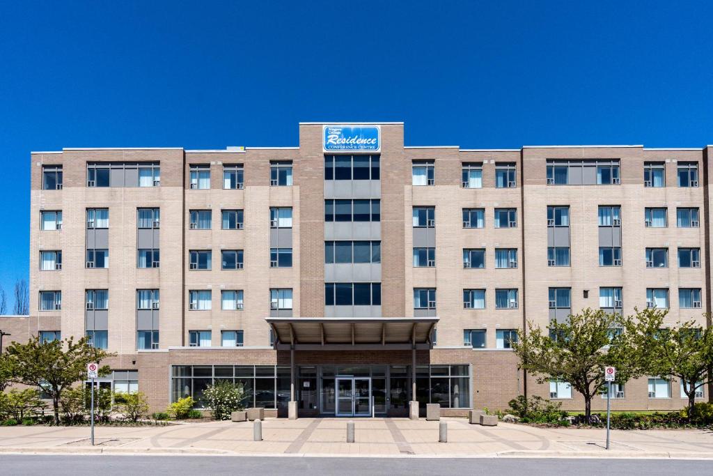 a large tan building with a sign on it at Residence & Conference Centre - Niagara-on-the-Lake in Niagara-on-the-Lake