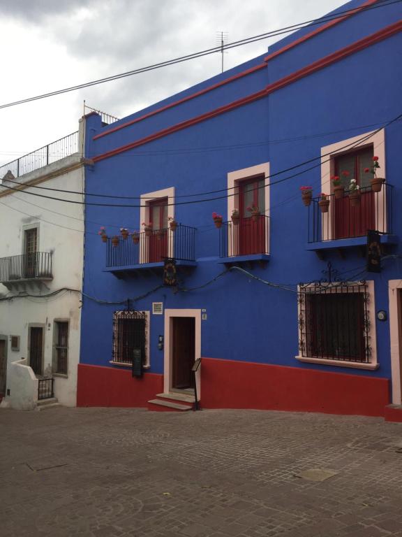 een blauw gebouw met rode deuren en ramen bij El Zopilote Mojado in Guanajuato