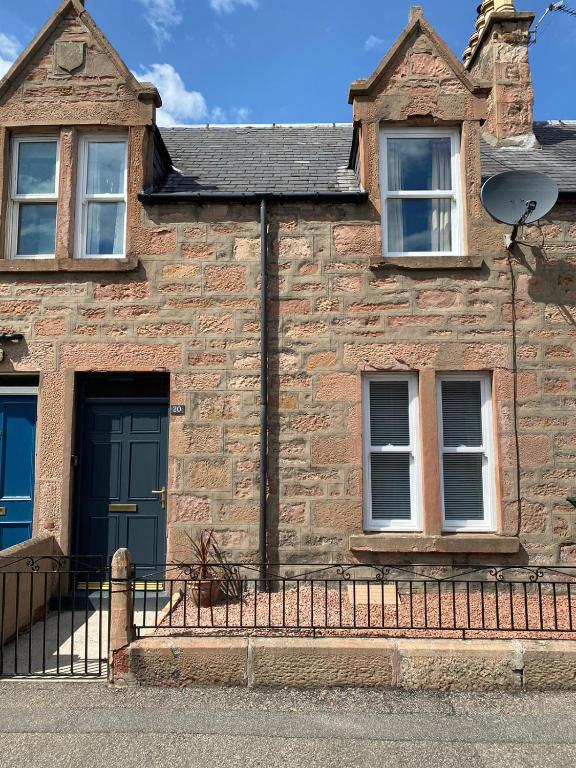 an old stone house with a blue door and windows at No. 20 in Inverness