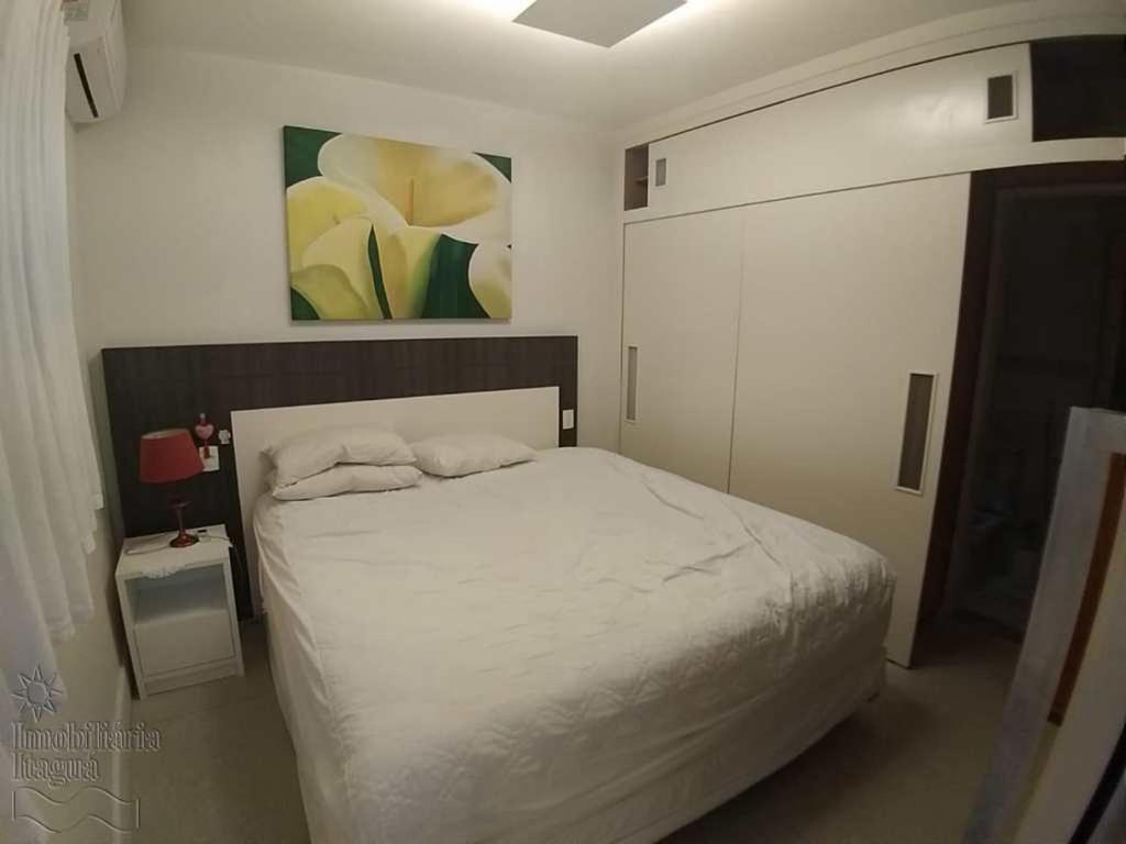 um quarto com uma cama branca e um quadro na parede em Cobertura Duplex Praia Grande Ubatuba em Ubatuba