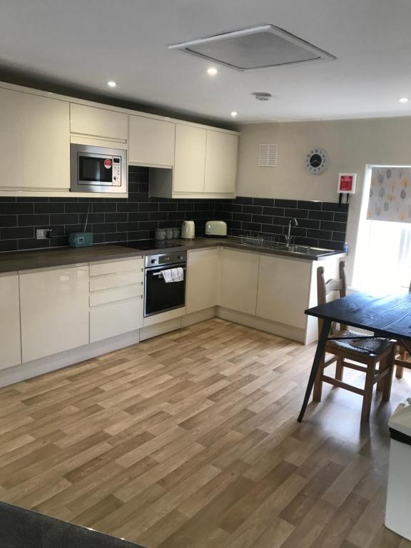 uma cozinha com armários brancos e piso em madeira em Flat 2, 22 the square centre of Dalston village em Dalston